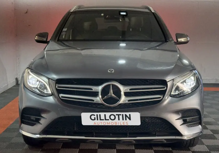Vue frontale d'un Mercedes GLC 250 Fascination 4Matic gris foncé avec phares LED allumés en intérieur.