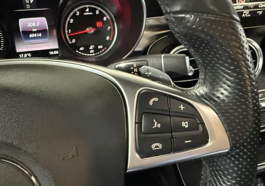 Gros plan sur le volant cuir perforé et les commandes multifonctions du tableau de bord du Mercedes GLC 250 Fascination gris foncé.