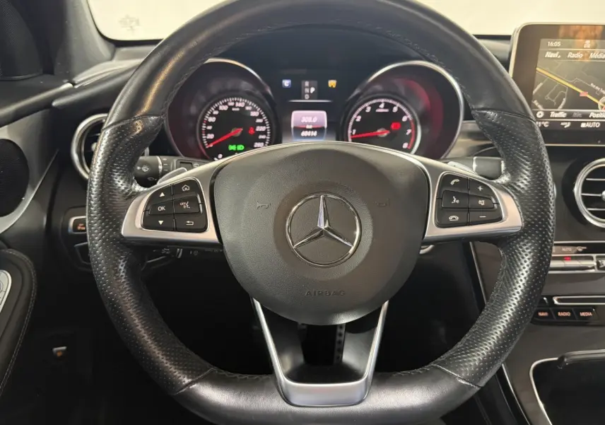 Vue rapprochée du volant cuir noir perforé de la Mercedes GLC 250 Fascination 2019 avec tableau de bord et écran multimédia.