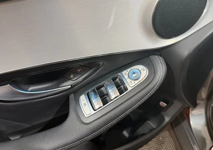 Gros plan sur la commande des vitres et rétroviseurs côté conducteur d’une Mercedes GLC 250 Fascination gris foncé.