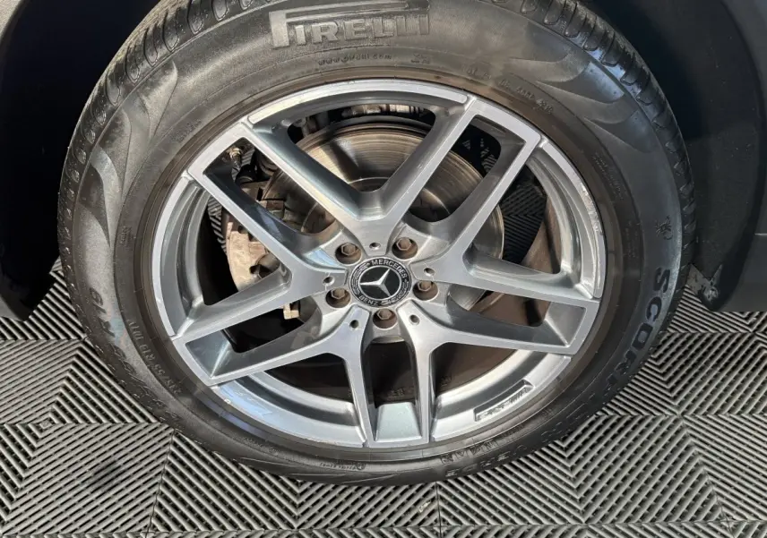 Gros plan sur la jante alliage argentée avec logo Mercedes d’un Mercedes GLC 250 Fascination 2019 gris foncé.