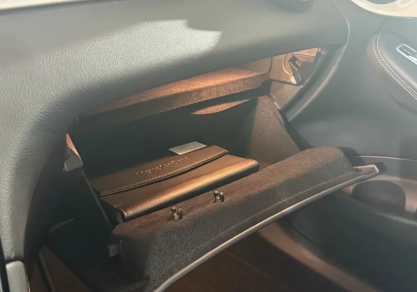 Gros plan de la boîte à gants ouverte côté passager dans l’habitacle noir d’un Mercedes GLC 250 Fascination 2019.