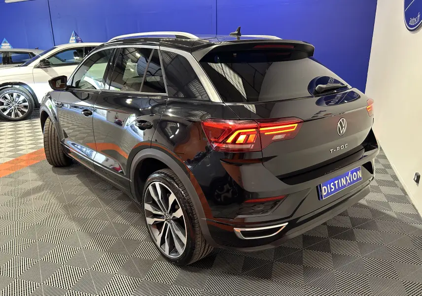 Vue 3/4 arrière droite d’un Volkswagen T-Roc noir avec feux LED allumés et jantes alliage en concession.