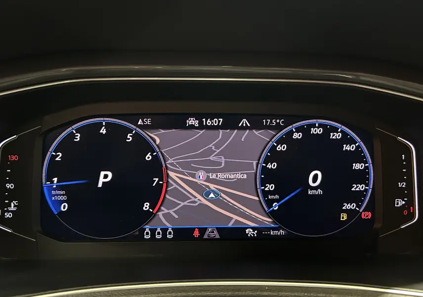 Tableau de bord numérique du Volkswagen T-Roc noir, affichant la navigation et les compteurs à l'arrêt.