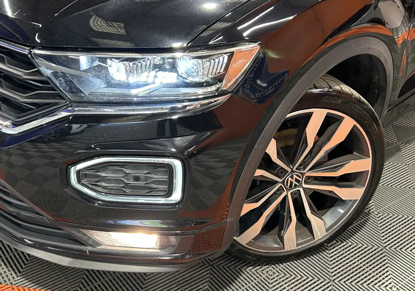 Gros plan sur l'avant droit noir du Volkswagen T-Roc 2020 avec phare LED allumé et jante alliage distinctive.