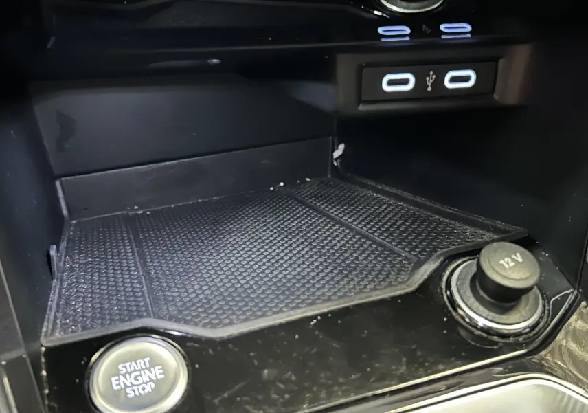 Gros plan intérieur sur la console centrale du Volkswagen T-Roc noir, montrant bouton start/stop, prise 12V et ports USB.