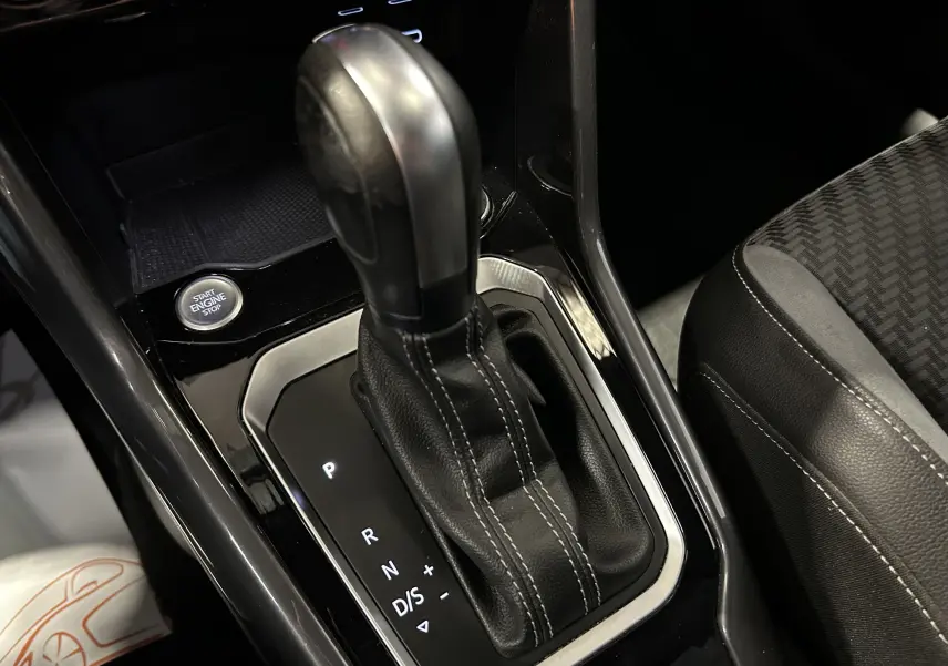 Gros plan sur la commande de boîte automatique et le bouton start/stop dans l’habitacle noir du Volkswagen T-Roc.