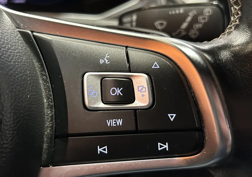 Gros plan sur les commandes multifonctions noires du volant côté gauche du Volkswagen T-Roc noir 2020.