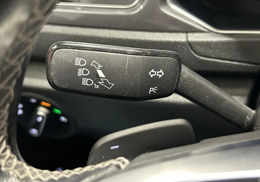 Gros plan sur la commande de clignotants et feux du Volkswagen T-Roc noir, côté gauche du volant.