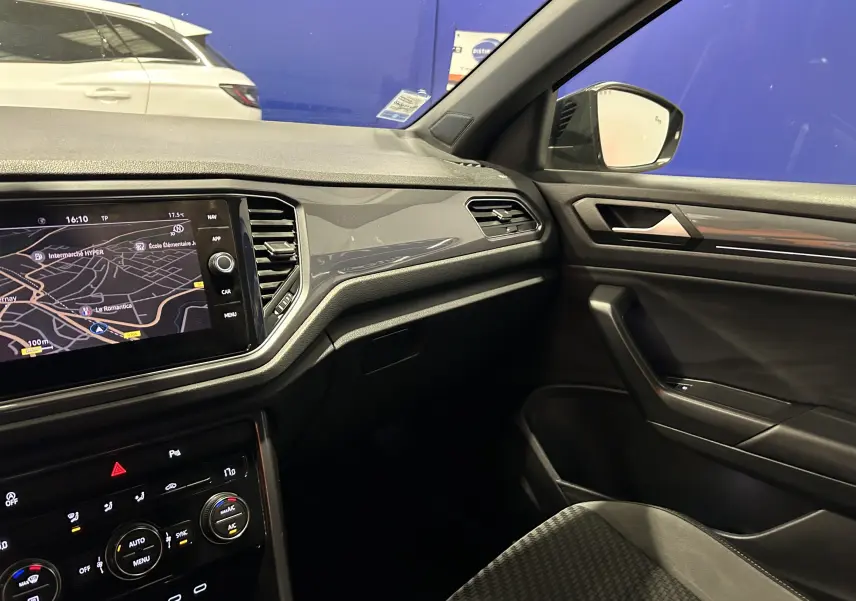 Intérieur côté passager du Volkswagen T-Roc noir 2020, avec tableau de bord moderne et écran tactile GPS allumé.