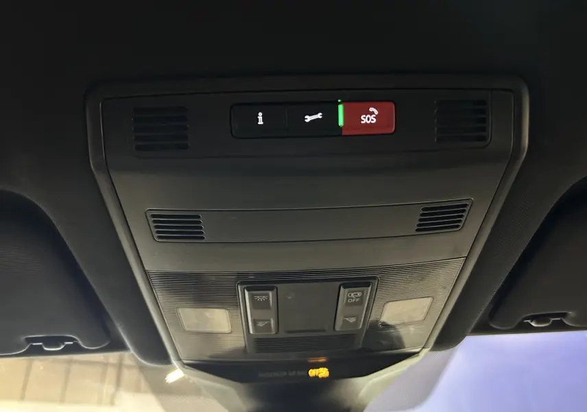 Vue en contre-plongée du panneau de commandes au plafond intérieur du Volkswagen T-Roc noir, avec bouton SOS illuminé en rouge.