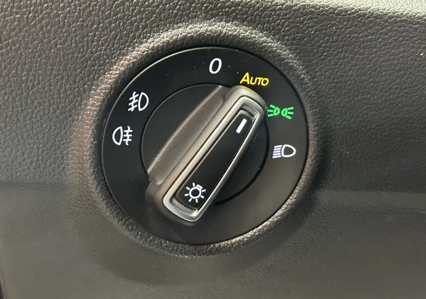Gros plan sur la molette de réglage des phares du Volkswagen T-Roc noir, avec fonction automatique activée.