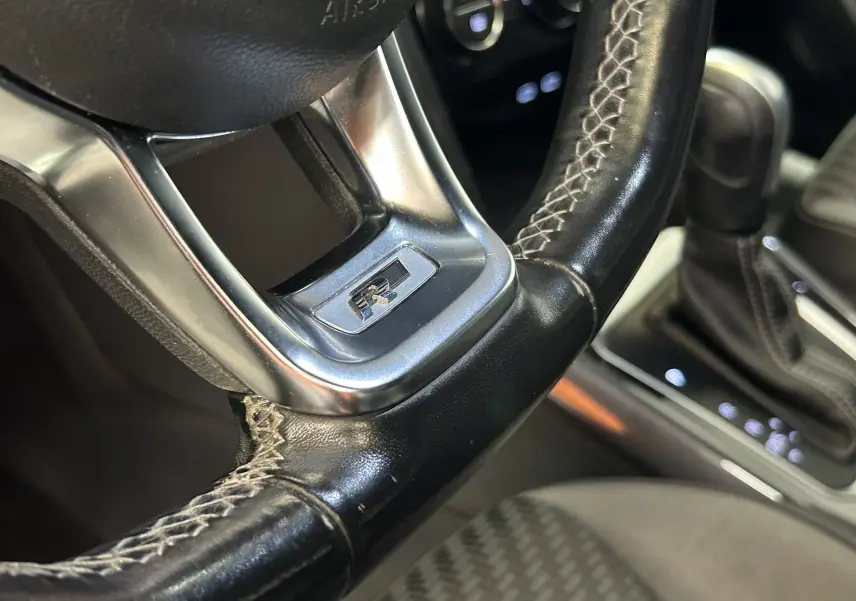 Gros plan sur le volant en cuir noir avec logo R, montrant aussi le levier de vitesses automatique du Volkswagen T-Roc.