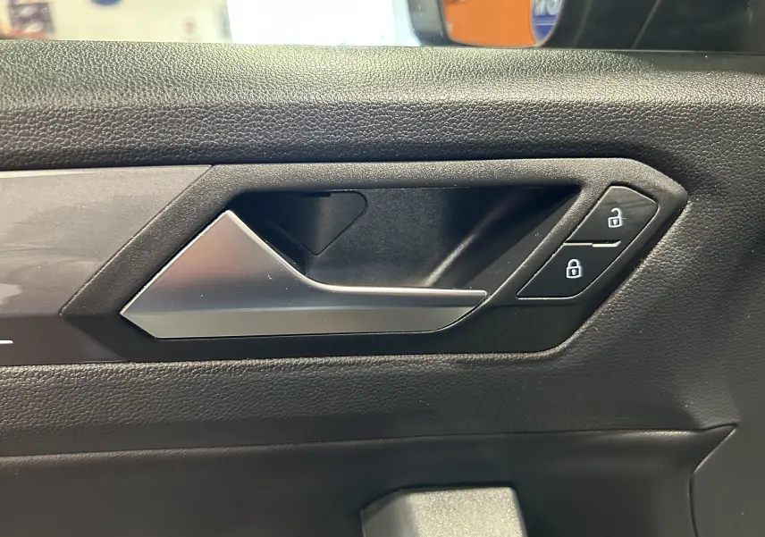 Poignée intérieure de porte côté gauche du Volkswagen T-Roc noir, avec boutons de verrouillage visibles.
