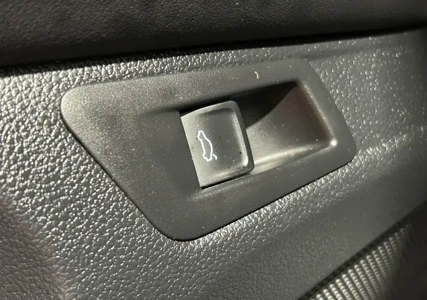 Gros plan sur le bouton d’ouverture électrique du hayon dans l’habitacle du Volkswagen T-Roc noir 2020.