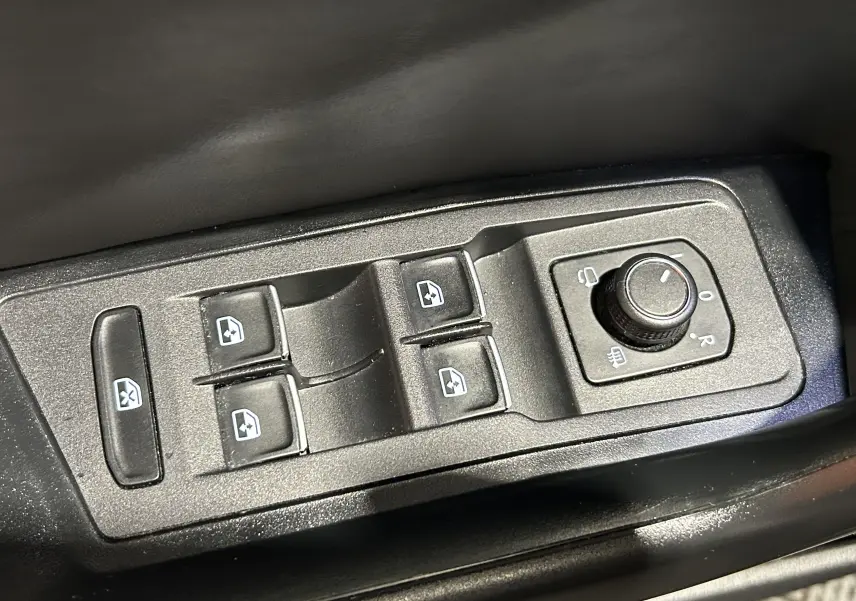 Panneau de commandes des vitres électriques et réglage des rétroviseurs dans un Volkswagen T-Roc noir, vue en plongée.