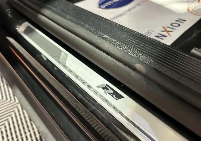 Gros plan sur la plaque de seuil de porte R-Line du Volkswagen T-Roc noir, côté gauche, intérieur visible.