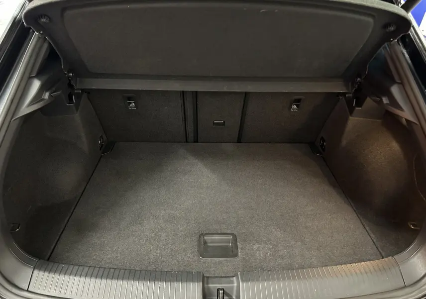 Coffre ouvert vu de l'arrière d'un Volkswagen T-Roc noir, montrant un espace de chargement propre et spacieux.