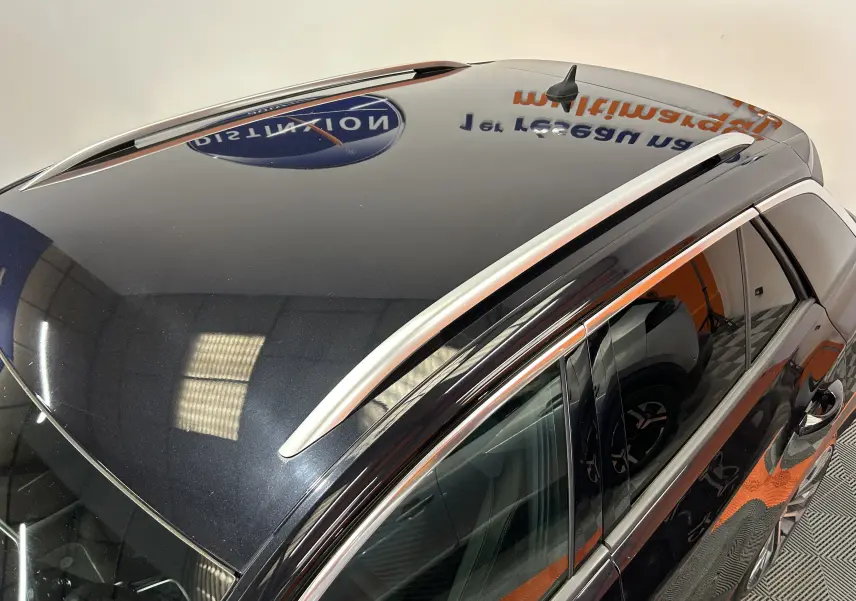 Vue plongeante sur le toit noir brillant d’un Volkswagen T-Roc avec barres de toit argentées et antenne requin.