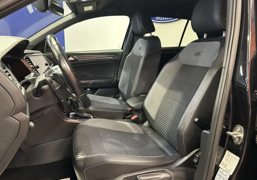 Vue intérieure côté conducteur du Volkswagen T-Roc noir 2020, mettant en valeur les sièges R-Line en cuir et alcantara.