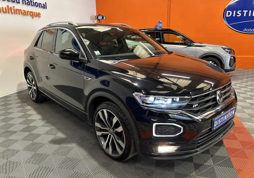 Volkswagen T-Roc noir en 3/4 avant droit avec phares LED allumés et jantes alliage distinctives R-Line.