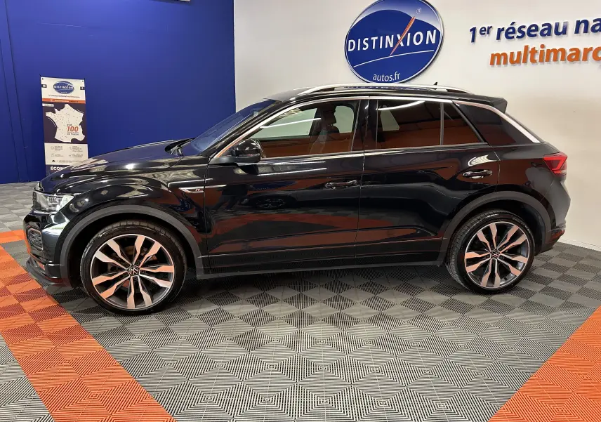 Profil côté gauche d'un Volkswagen T-Roc noir 2020 en finition R-Line avec jantes alliage bicolores, dans un showroom.