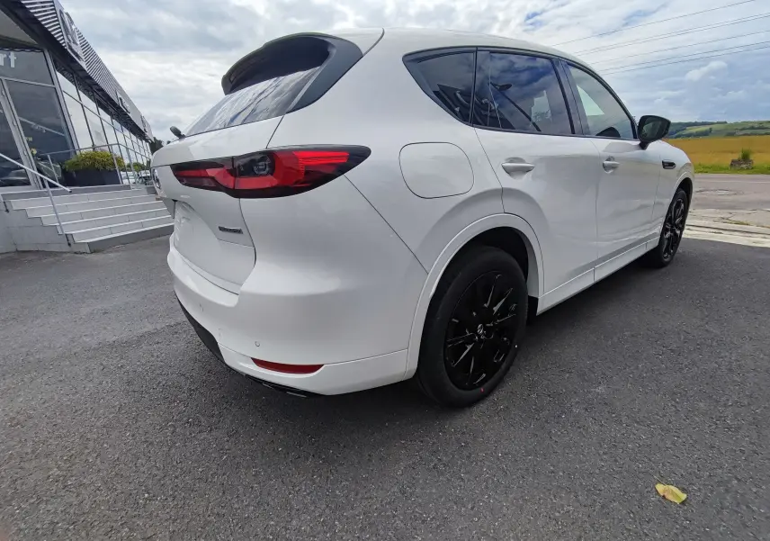 Vue 3/4 arrière droite du Mazda CX-60 blanc métal, avec jantes noires et feux arrière LED distinctifs.