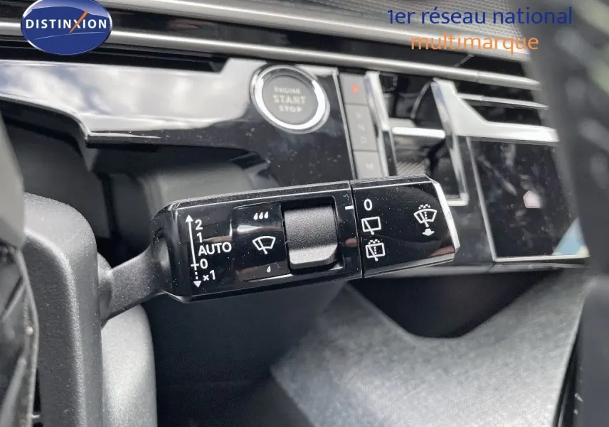 Gros plan sur la commande d'essuie-glace du Peugeot 5008 Hybrid 2025 avec tableau de bord noir brillant et bouton start/stop visible.