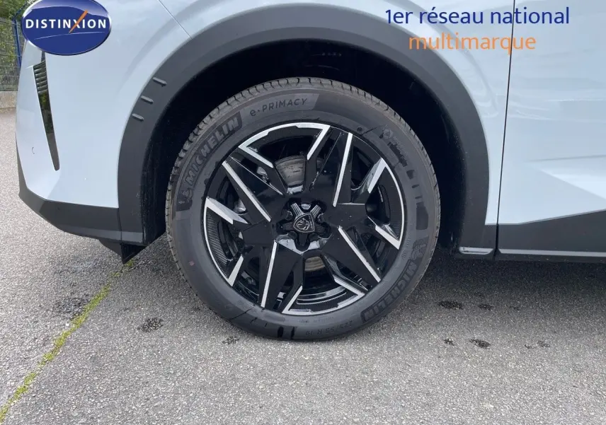 Gros plan sur la roue avant gauche du Peugeot 5008 blanc Okenite métal avec jante noire et détails argentés.