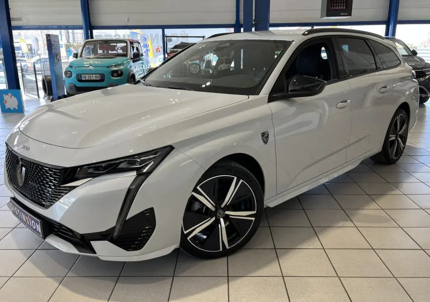 Peugeot 308 SW BlueHDi blanc okenite vue 3/4 avant droit, calandre noire et jantes alliage 18 pouces.