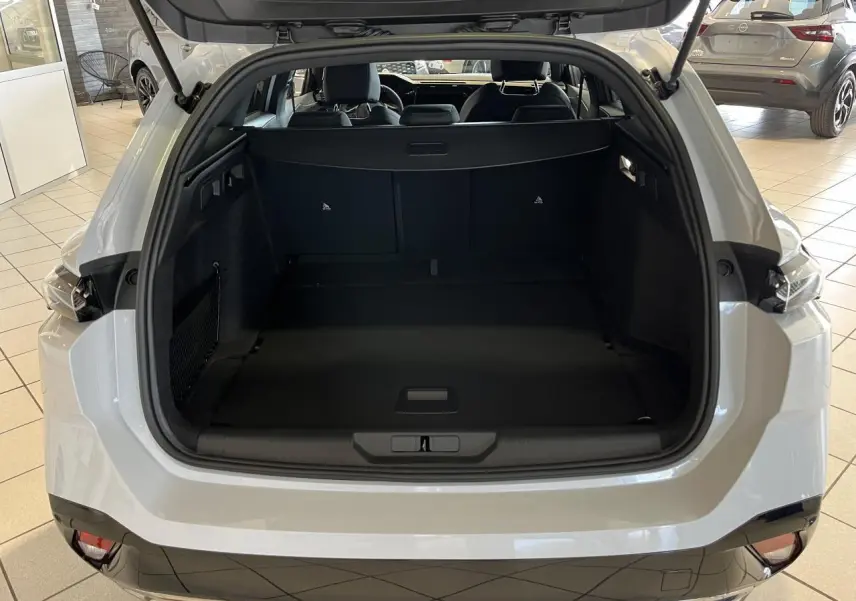 Coffre ouvert vu de l'arrière d'une Peugeot 308 SW blanc okenite avec intérieur noir et feux arrière LED griffés.