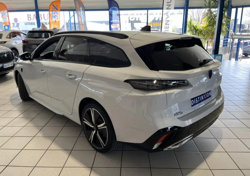 Peugeot 308 SW BlueHDi 130ch GT blanc okenite vue 3/4 arrière droit en showroom avec jantes alliage noires.