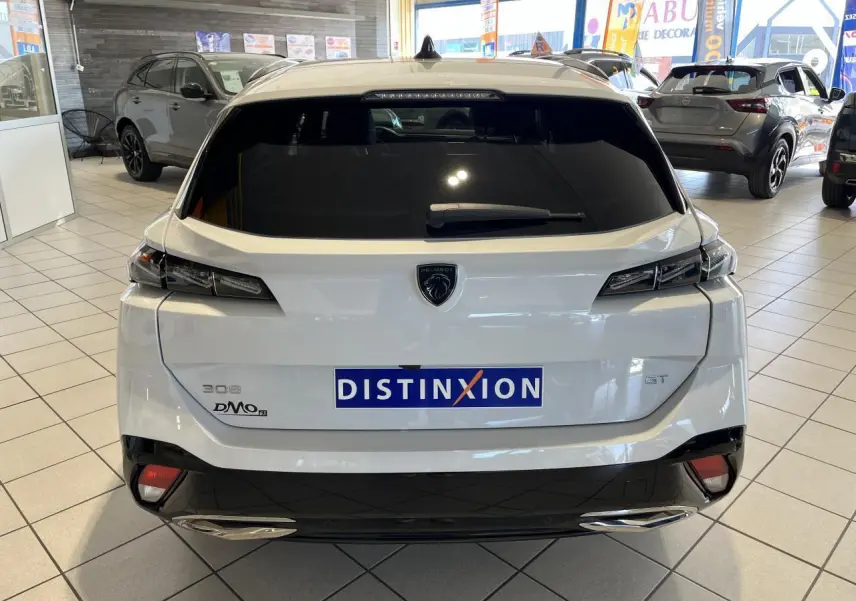 Vue arrière d'une Peugeot 308 SW GT blanche Okenite avec feux arrière LED et double sortie d'échappement chromée en concession.