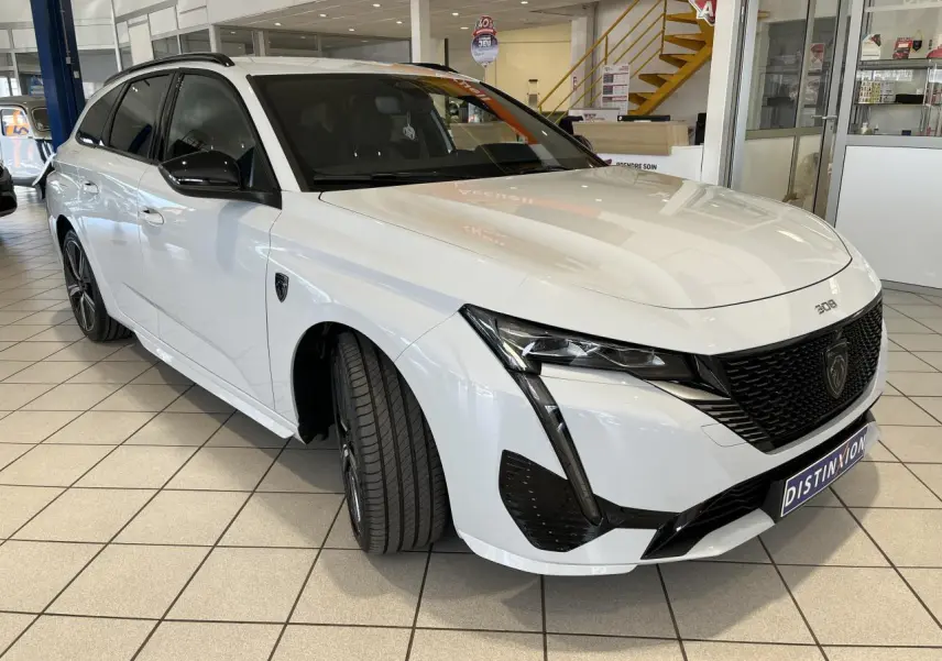 Peugeot 308 SW BlueHDi 2025 blanc okenite vue 3/4 avant droit avec calandre noire et jantes alliage 18 pouces.