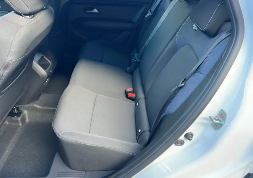 Vue intérieure sur la banquette arrière du Dacia Duster blanc glacier 2025, montrant les sièges en tissu gris et bleu.