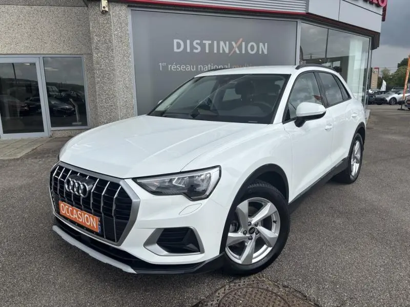 Audi Q3 blanc Glacier métallisé vue 3/4 avant droit, calandre chromée et jantes alu 5 branches visibles.