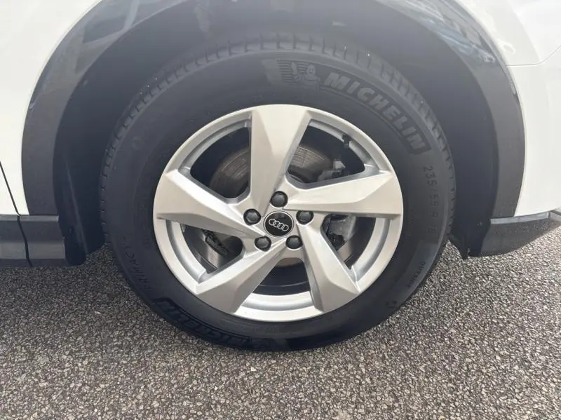 Gros plan sur la roue avant droite d'un Audi Q3 blanc Glacier métallisé avec jante alu 5 branches et pneu Michelin.