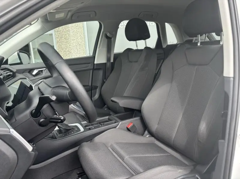 Vue intérieure côté conducteur de l'Audi Q3 35 TFSI 2022, sièges sport en tissu gris et volant cuir multifonction.