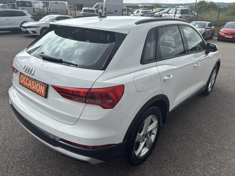 Audi Q3 blanc Glacier métallisé vue 3/4 arrière droit, avec feux LED et jantes alliage 18 pouces.
