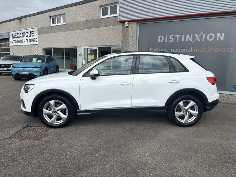 Audi Q3 blanc Glacier métallisé vue de profil côté gauche, avec jantes alliage et détails noirs contrastants.