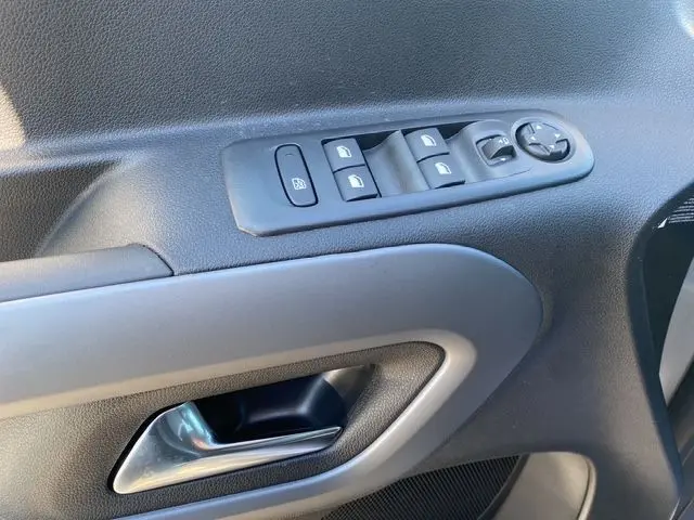 Gros plan sur la commande des vitres et le bouton de réglage des rétroviseurs côté conducteur du Citroën Berlingo gris Artense.