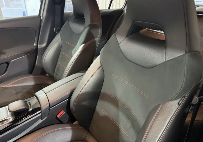 Vue rapprochée des sièges avant en cuir noir avec surpiqûres rouges dans l’habitacle d’une Mercedes Classe A AMG Line 2021.