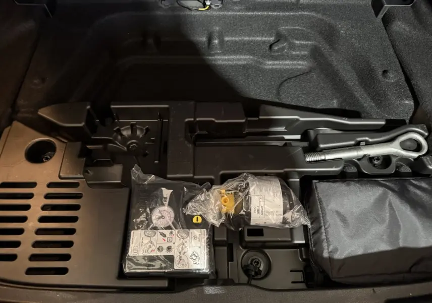 Vue rapprochée du coffre avec kit de réparation pneus et outils dans une Mercedes Classe A 200 AMG Line gris foncé 2021.