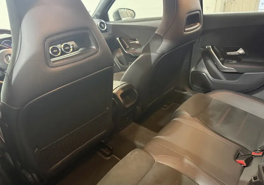 Vue intérieure arrière montrant les sièges noirs avec surpiqûres rouges et le dossier des sièges avant d'une Mercedes Classe A AMG Line 2021.