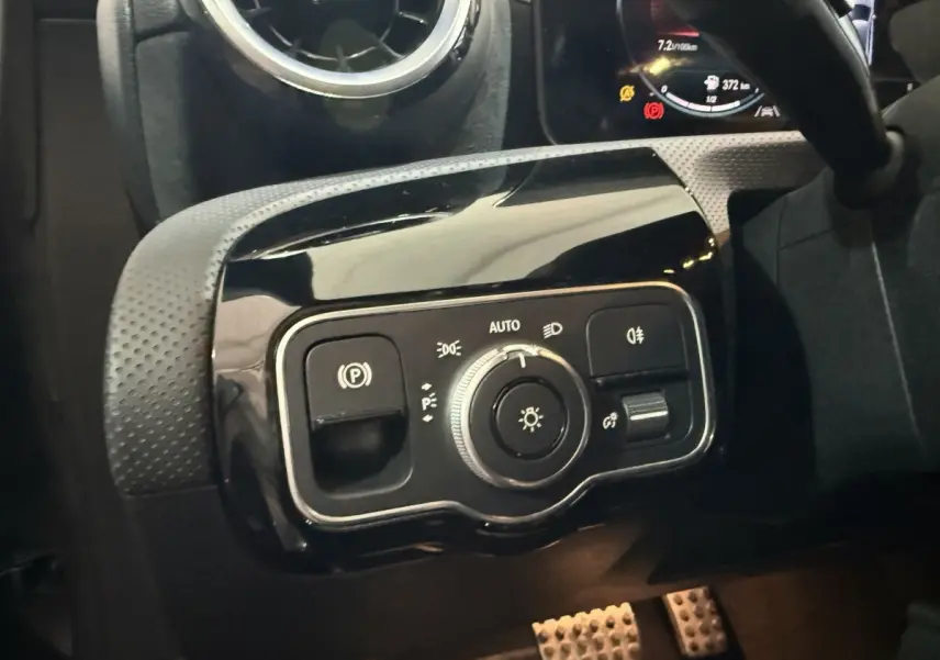 Gros plan sur le panneau de commande des phares et du frein à main électrique dans une Mercedes Classe A A 200 AMG Line 2021.