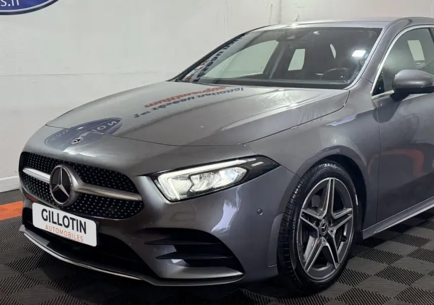 Vue 3/4 avant droite d'une Mercedes Classe A 200 AMG Line gris foncé avec jantes alliage et phares LED allumés.