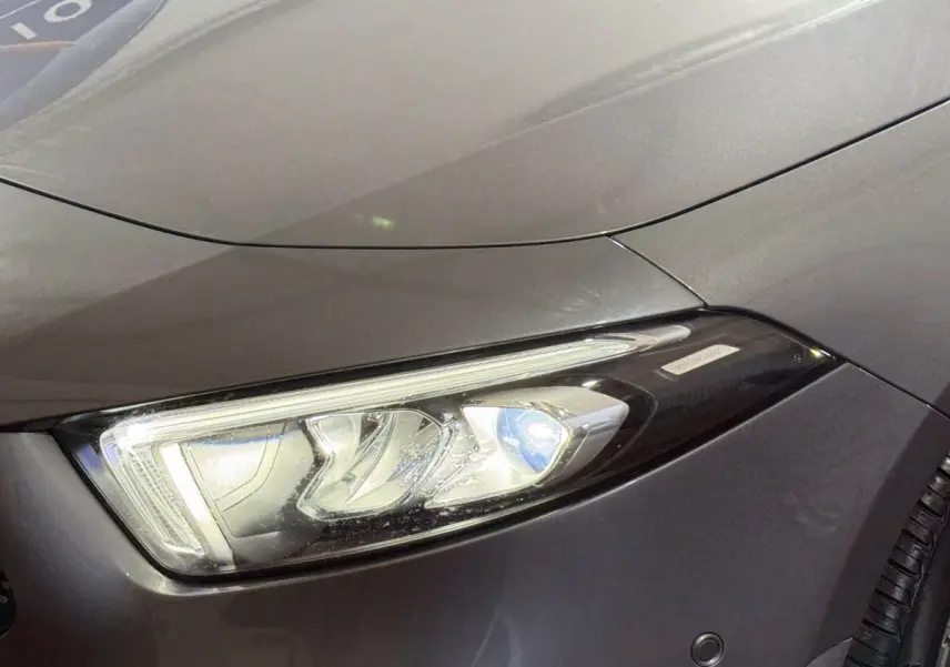 Gros plan sur le phare avant droit d’une Mercedes Classe A 200 AMG Line gris foncé, mettant en valeur les détails LED.
