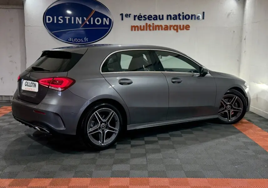 Vue latérale droite d'une Mercedes Classe A 200 AMG Line gris foncé, avec jantes alliage et feux arrière LED allumés.