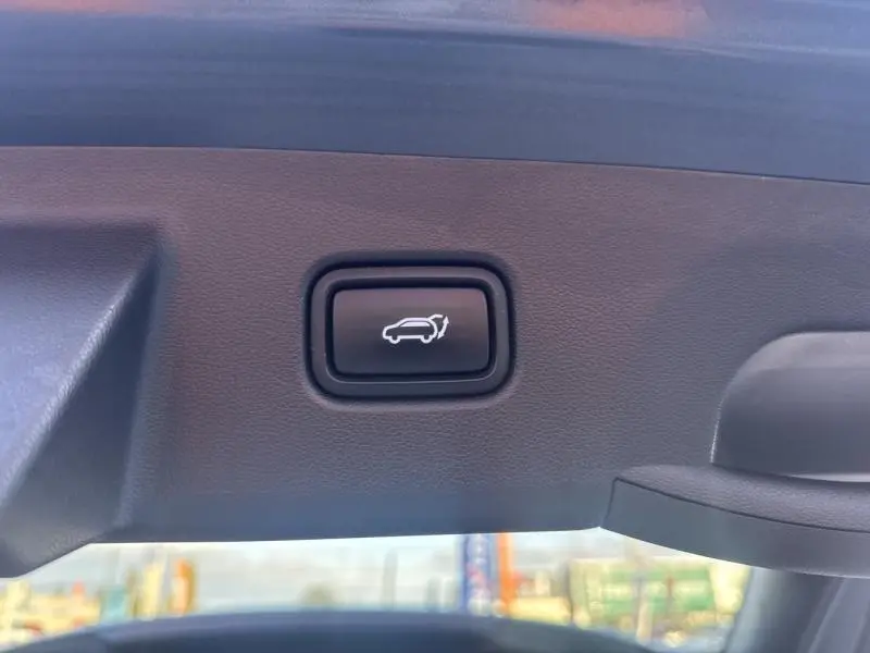 Bouton noir d'ouverture électrique du hayon sur le bord intérieur du coffre du Hyundai Tucson Teal Blue Métal.