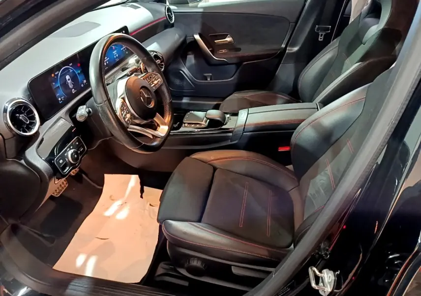 Vue intérieure côté conducteur de la Mercedes Classe A 200 AMG Line 2021 avec sièges noirs et tableau de bord digital.
